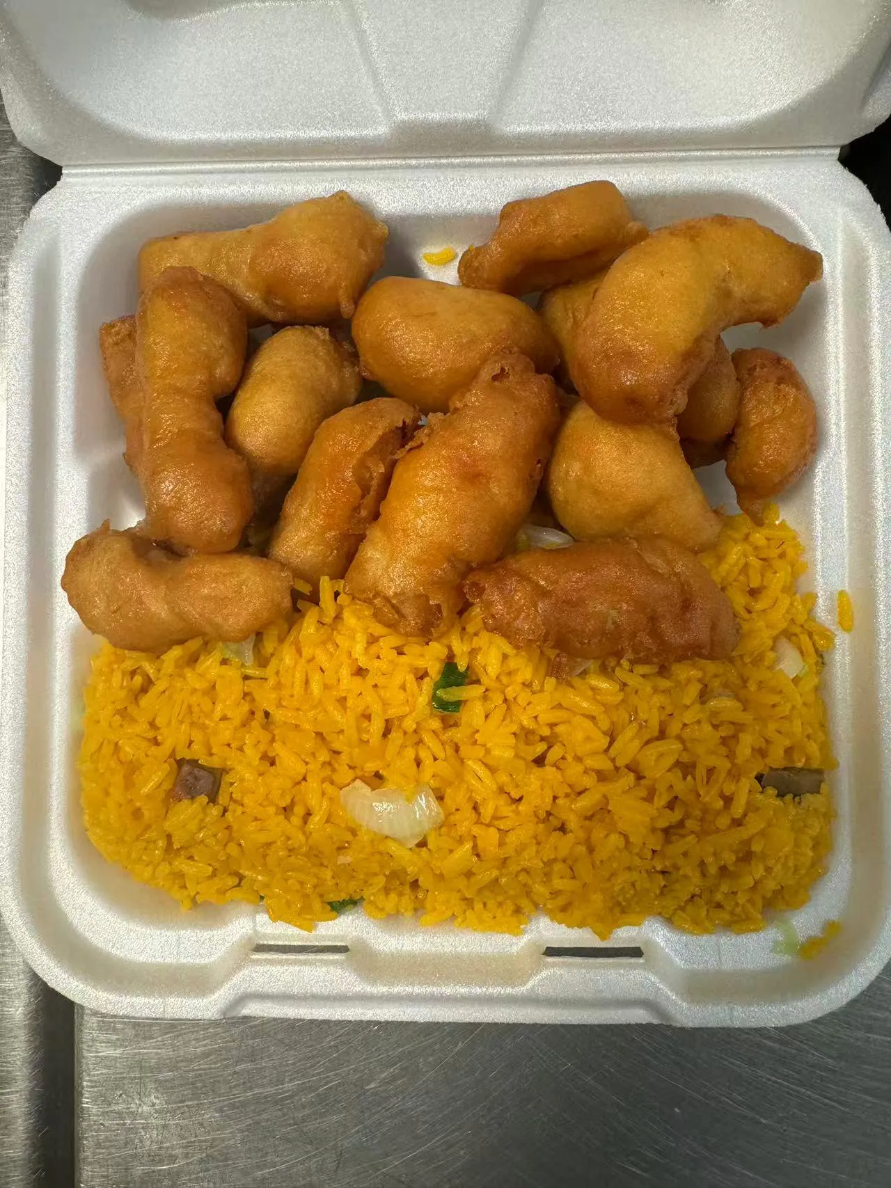 Crispy fried chicken balls over yellow rice in a takeout box